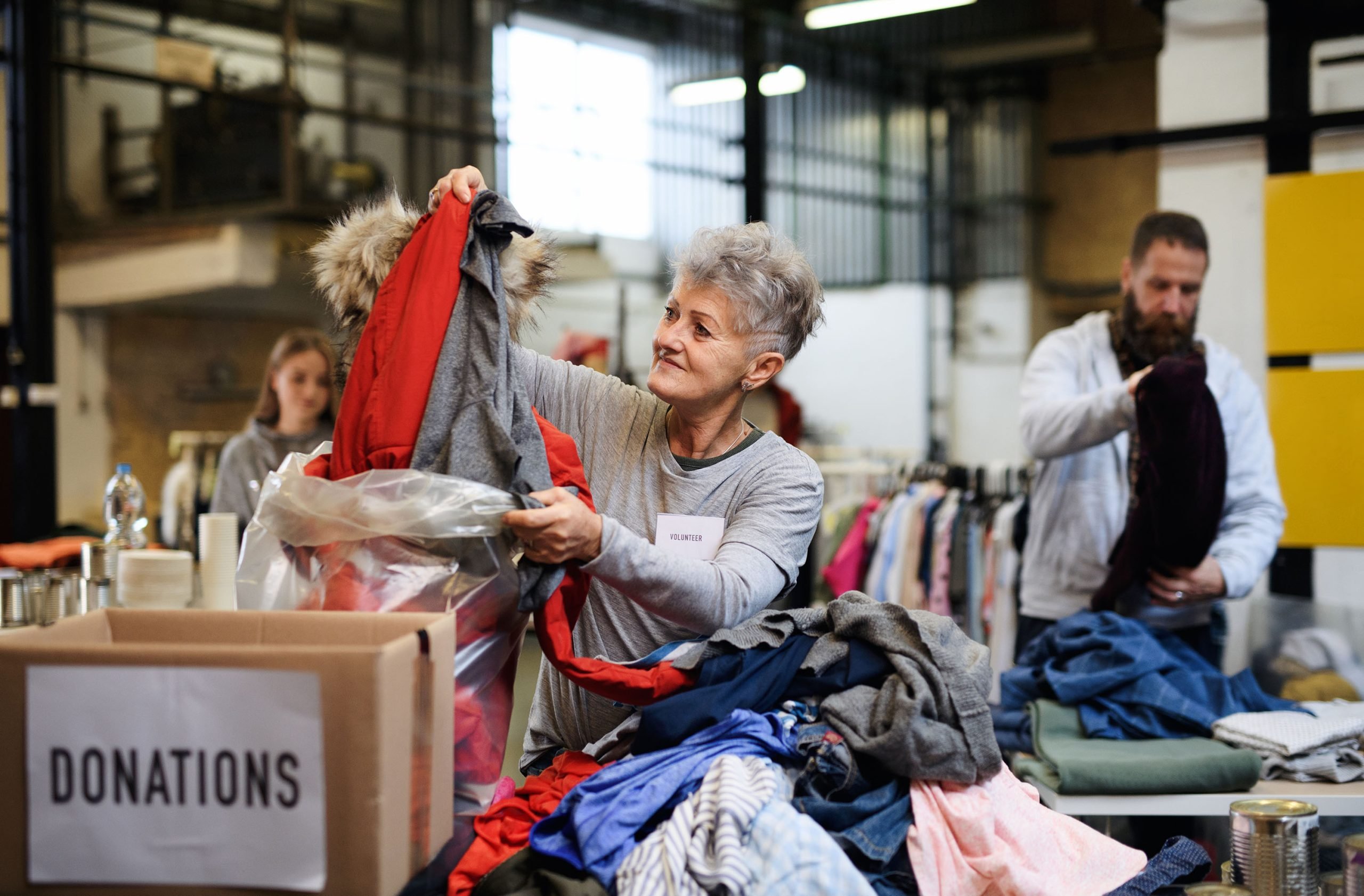 Volunteers sorting out donated clothes in community charity donation center, coronavirus concept.